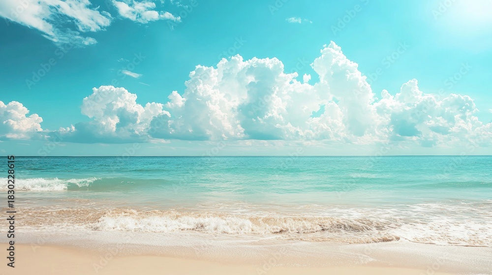 Fototapeta premium A serene beach scene with a clear blue sky and white clouds, a calm ocean, and a sandy shore.