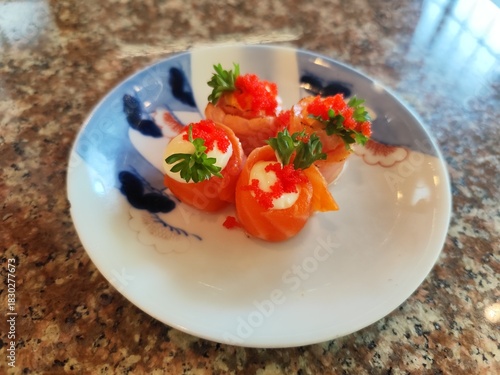 Sushi wrapped in salmon on a tile plate