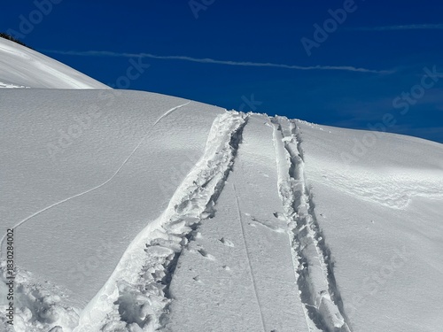 Wonderful winter hiking trails and traces in the fresh alpine snow cover of the Swiss Alps and over the village of St. Antönien - Canton of Grisons, Switzerland (Kanton Graubünden, Schweiz)