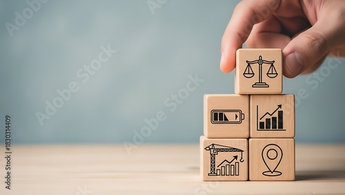 Building a foundation Hand arranging blocks with law, energy, growth, location, and progress