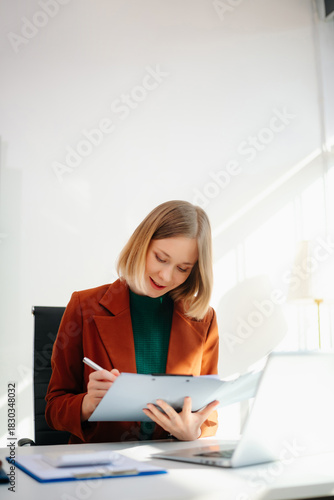 Business woman reviewing documents at desk in modern office. Ideal for finance, marketing, startup