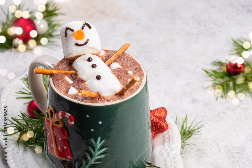 Fototapeta premium Cozy winter scene with festive hot chocolate topped by a playful snowman in a decorated mug