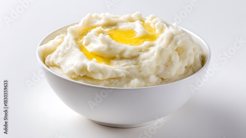 White ceramic bowl filled with creamy mashed potatoes and butter topping isolated on white background