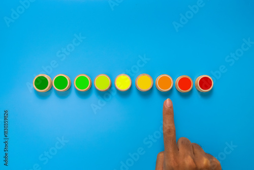 male hand point risk level meter indicator from low to high on wooden blocks. isolated on blue background. concept of risk management