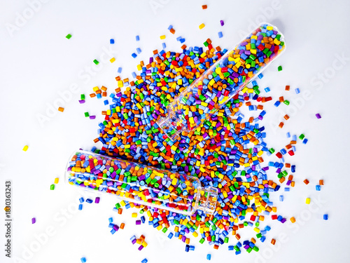 Colorful polymer masterbatch gradation, colorful pigment resin pellets in glass tubes poured on a white background, suitable as a product catalog design for industrial plastic manufacturing companies