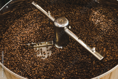 Coffee Roster machine working cooldown roasted coffee beans. Hot brown coffee bean in bucket.  
