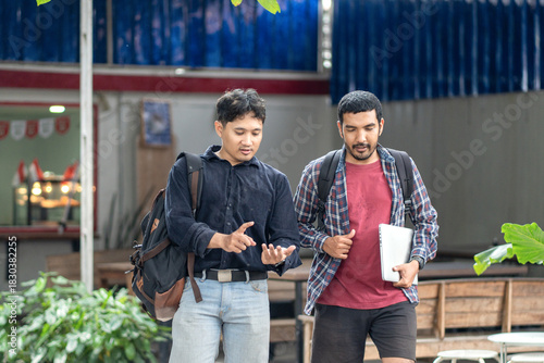 Two Asian men walking and discussing work outdoors