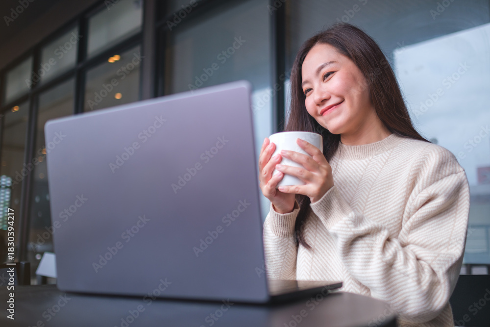 Fototapeta premium Portrait image of a woman working on laptop computer while drinking coffee in cafe