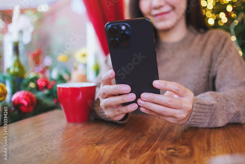 Closeup image of a woman holding and using mobile phone in Christmas holiday
