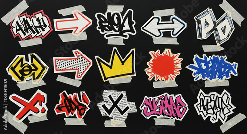 Collection of street art graffiti stickers, arrows, crown, and splatters taped onto a surface
