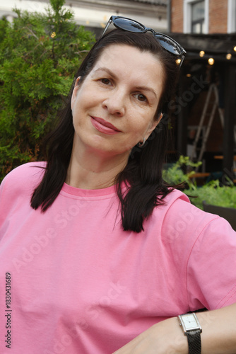 Portrait of a Caucasian brunette in a pink T-shirt on a city street.