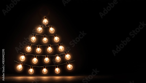 Minimalist Christmas tree made from glowing light bulbs arranged in a pyramid shape on a dark background, creating a warm and modern holiday atmosphere. Banner with copy space