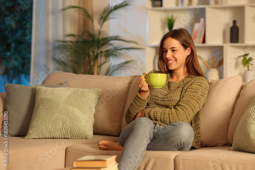 Happy woman in green in the night at home drinking coffee