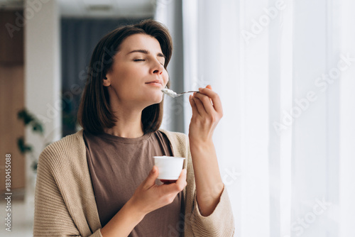 Obraz na płótnie Smiling woman enjoying healthy yogurt for breakfast or snack