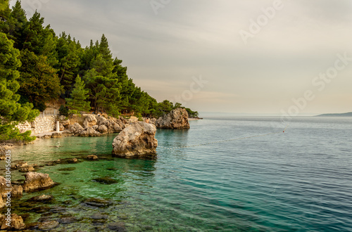 Fototapeta Naklejka Na Ścianę i Meble -  Croatia's Adriatic coast in Dalmatia on the Makarska Riviera, with the Biokovo Mountains and forests in the background. Golden hour with beautiful beaches and a rocky coastline.