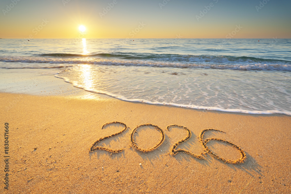 Naklejka premium 2026 text symbol of new year on the sea sand beach shore during sunset.