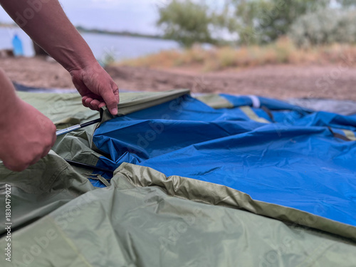 Person setting up a tent for outdoor camping
