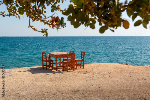 Fototapeta Naklejka Na Ścianę i Meble -  Wooden table and chairs on a beach by the Mediterranean Sea.