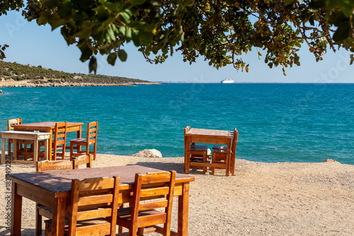 Fototapeta Naklejka Na Ścianę i Meble -  Wooden tables and chairs in a beach park on the Mediterranean coast.