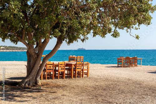 Fototapeta Naklejka Na Ścianę i Meble -  Wooden tables and chairs in a beach park on the Mediterranean coast.