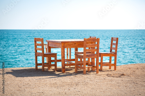 Wooden table and chairs on a beach by the Mediterranean Sea.