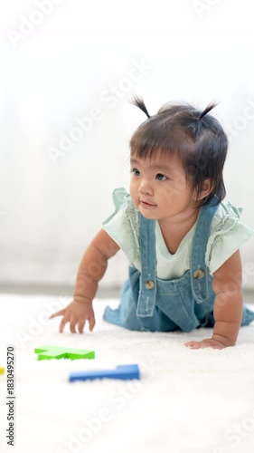 Asian toddler girl crawling forward on carpet smiling with joy, slowmotion Vertical capture of playtime movement, early motor skill development, happy childhood learning moment at cozy home