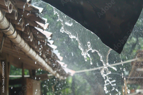 Billede på lærred rainwater flowing heavily from the roof of a traditional house in the midst of h