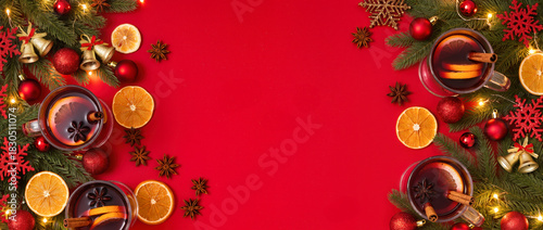 Christmas mulled wine with cinnamon, orange slices, star anise and festive decorations on red background. Warm holiday drink scene with copy space.