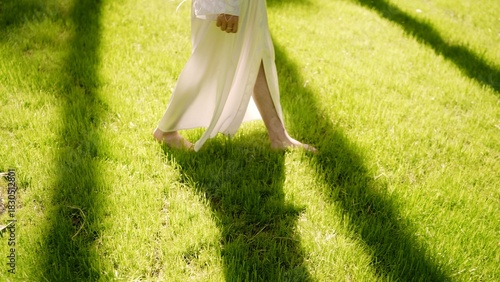 Jesus walking barefoot on green grass in sunlight