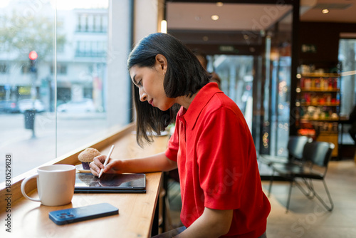 Woman creative professional drawing on tablet at cafe