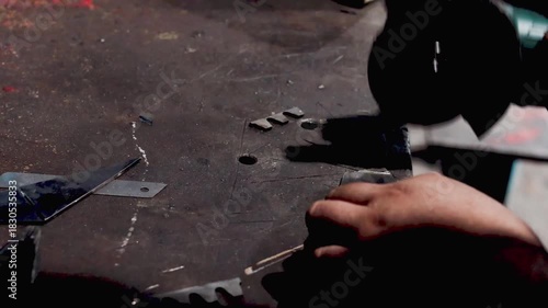 ​Close-up of a worker's hands using an angle grinder to cut metal, generating a dramatic shower of bright yellow and orange sparks, symbolizing heavy industry, construction, and metalworking.