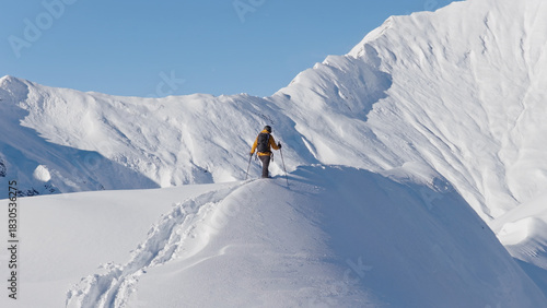 Aerial photo of a ski mountaineer ascending a snowy alpine ridge in Austria. Winter landscape, backcountry adventure, and solitude in breathtaking mountain scenery.