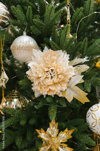 Elegant christmas tree with white and gold decorations and a large flower