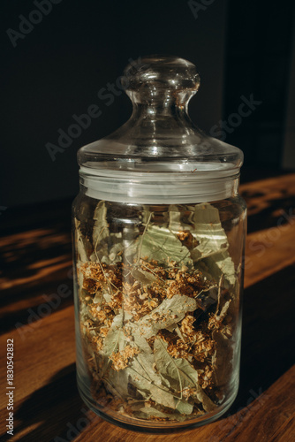 Linden leaves in a closed glass jar close up. Vertical photo. Glass transparent jar with linden - herbal tea eco collection