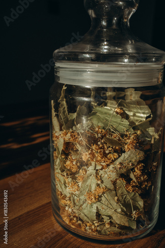 Linden leaves in a closed glass jar close up. Vertical photo. Glass transparent jar with linden - herbal tea eco collection