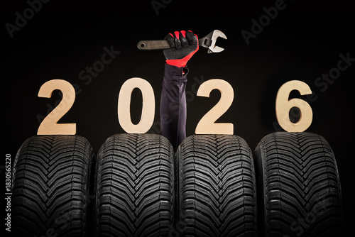 Winter car tires service and thumbs up hands of mechanic and text 2026 happy new year on black background