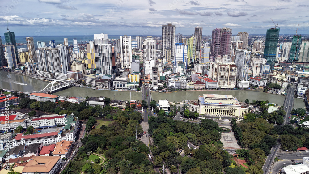 Fototapeta premium High angle drone view from Intramuros looking toward Binondo, the Chinatown district of Manila, Philippines. The scene shows a dense mix of colorful high-rise buildings along the Pasig River, bridges