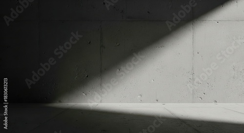Dramatic diagonal beam of sunlight illuminating a rough, textured concrete wall and floor surface