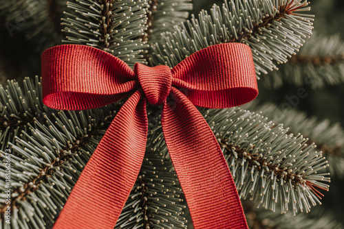 Close up of a red bow tied on a green christmas tree branch