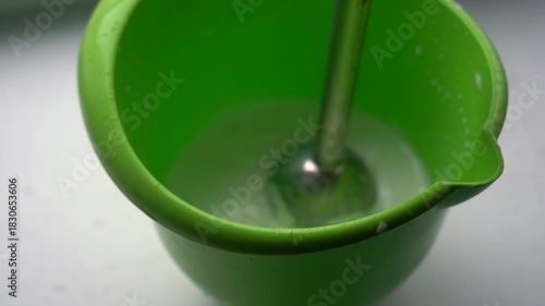 A Close-Up View of a Green Mixing Bowl with a Blending Tool, Capturing the Transformation of Liquid into Foam During a Culinary Process. Video with sound