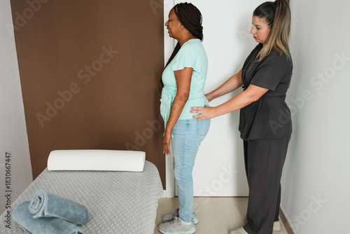 Senior african woman carrying out an assessments to ensure correct body posture - Medical and healthcare concept for elderly people - Main focus on therapist face