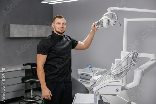 Male dentist adjusting dental light in modern clinic