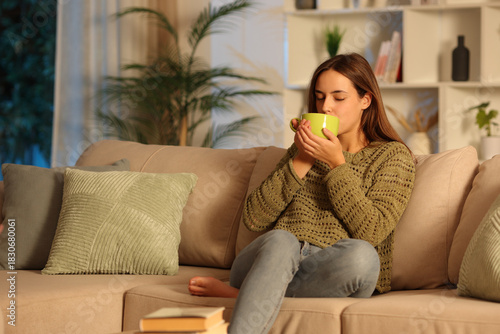 Woman in green drinking coffee or tea in the night at home