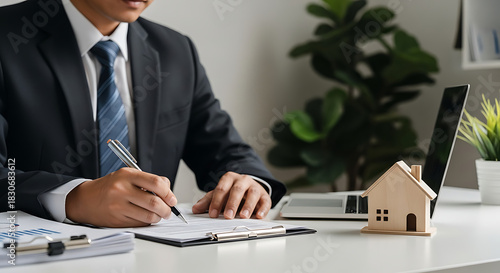 Real Estate Agent Signing Contract with Wooden House and Laptop