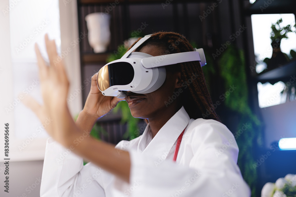 Naklejka premium Portrait happy African female doctor using virtual reality headset in medical innovation concept, gesture with finger to press button, sunlight