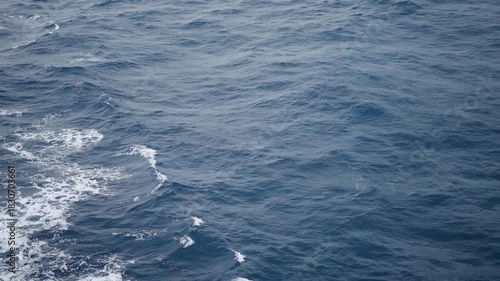 4K Full frame slow motion shot of sea waves as seen from the middle of the Andaman sea from a boat. Sea water on a blue sea during an overcast day. Ocean background with copy space. 