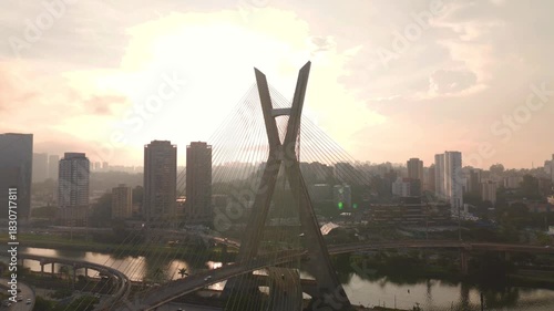 aerial view of a cable stayed bridge in Sao Paulo city during sunset with skyscrapers, traffic and a river