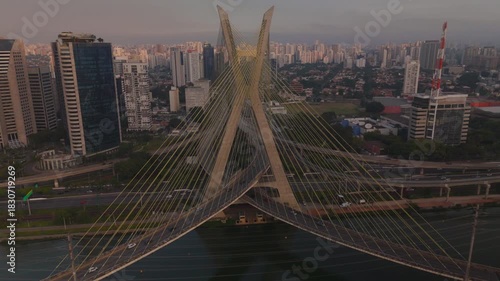 aerial view of a cable stayed bridge in Sao Paulo city during sunset with skyscrapers, traffic and a river