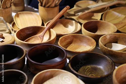 Assortment of handmade wooden bowls, spoons, and dishes in natural brown tones at a market stall