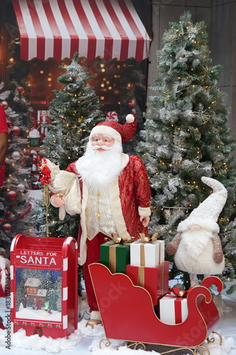 Christmas scene with Santa Claus figure, red sleigh with gifts and illuminated snowy trees, perfect for festive promotions